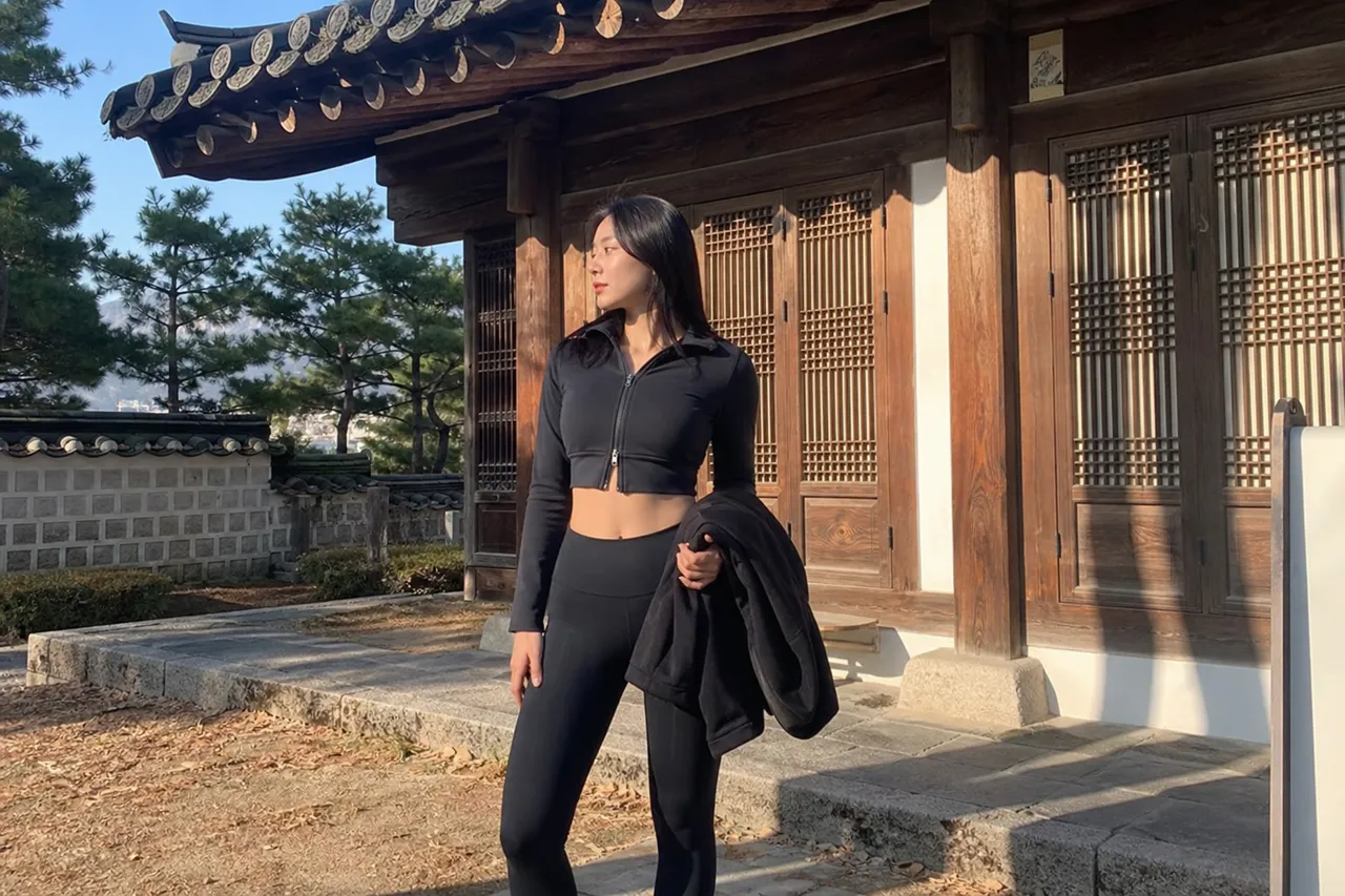 A serene photograph of a object in stylish leggings and a cropped jacket, posing in front of a traditional Korean Hanok, blending modern sportswear with classic architecture, morning sunlight, no people, objects and environment only