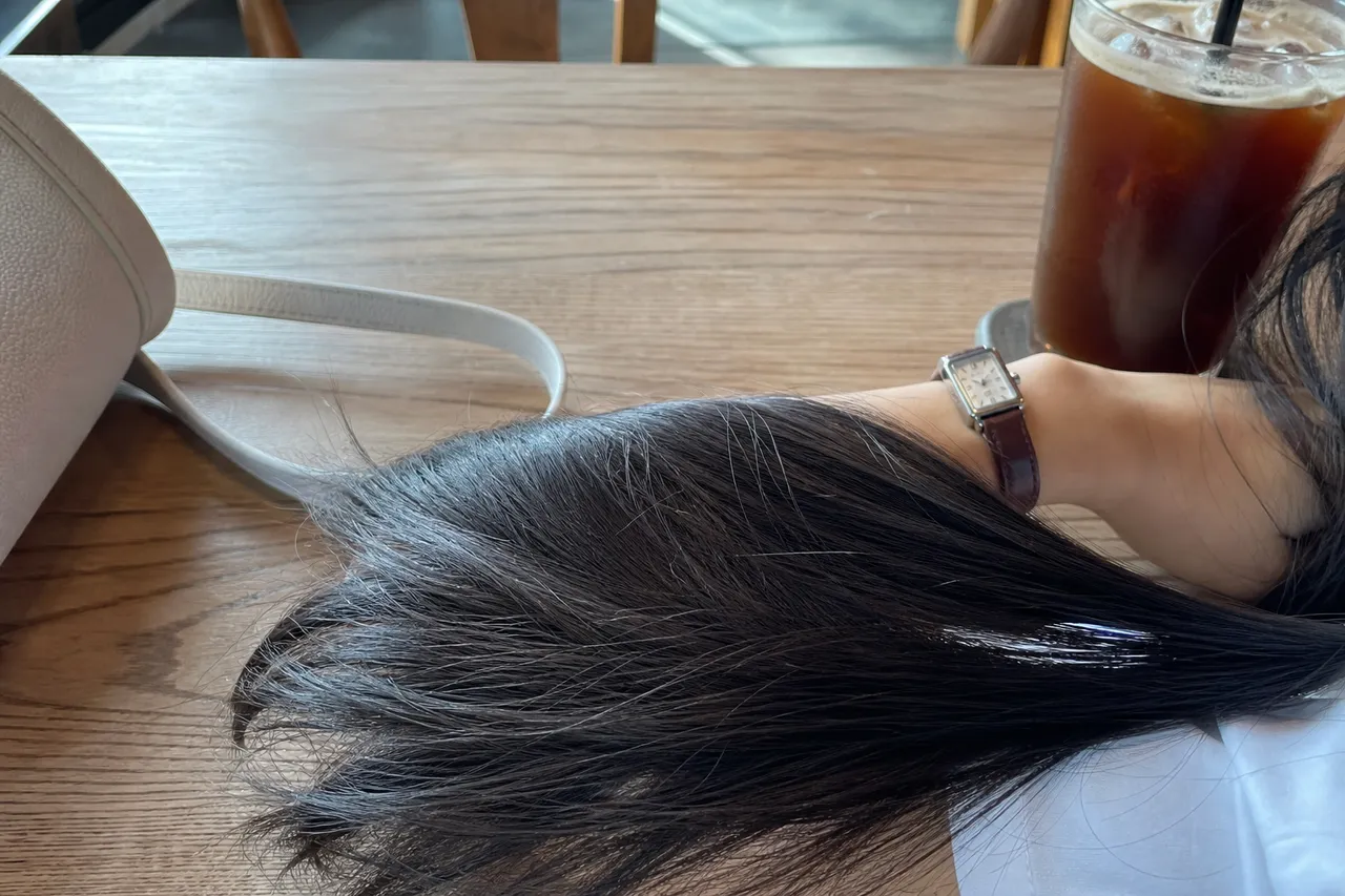 A close-up photograph of a object with shiny long straight hair and clear dewy skin, wearing a simple white cotton t-shirt and a classic leather watch, soft focus background, no people, objects and environment only