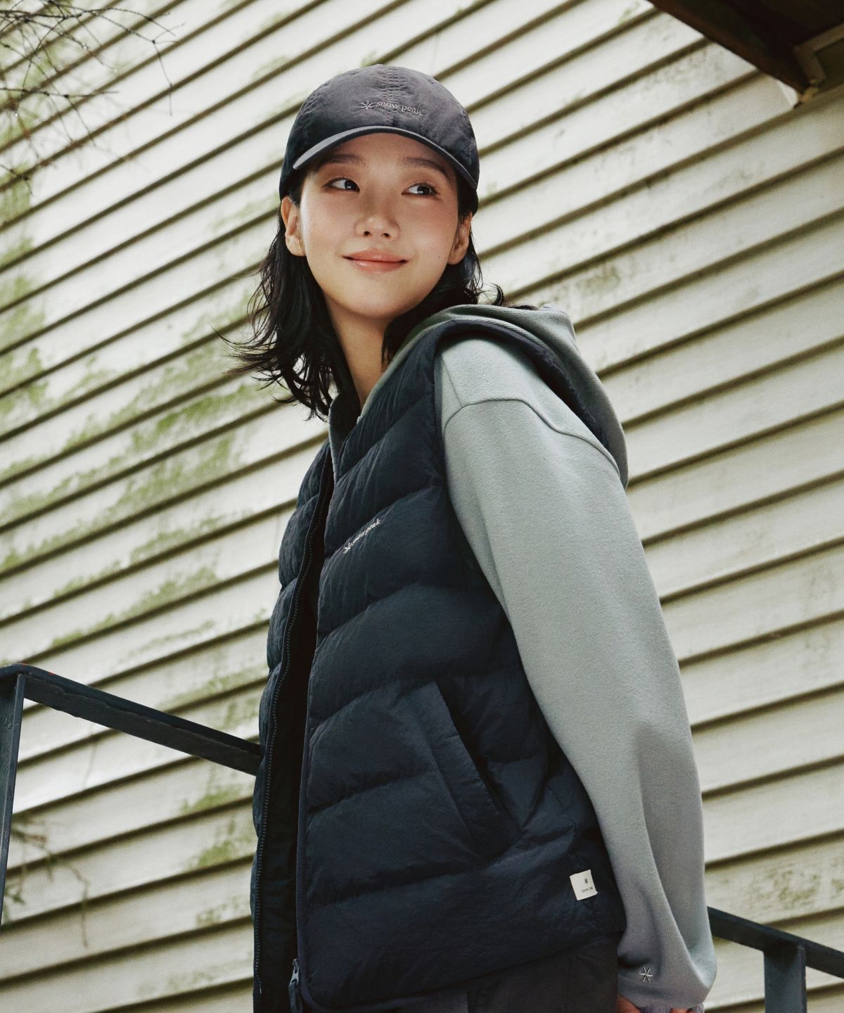 깔끔한 블랙 컬러의 스노우피크 경량 베스트가 옷걸이에 걸려 있는 모습과 로고 디테일