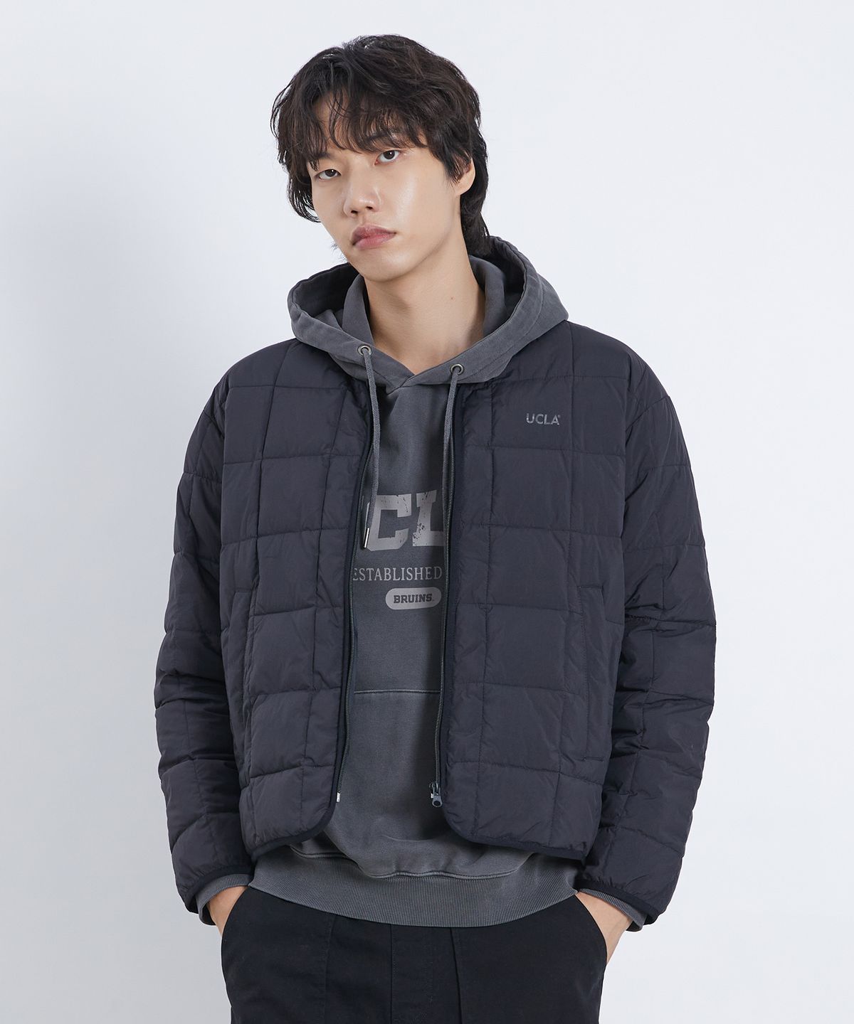 깔끔한 블랙 컬러의 유씨엘에이 경량 사각 퀼팅 집업 점퍼가 침대 위에 예쁘게 놓여 있는 모습