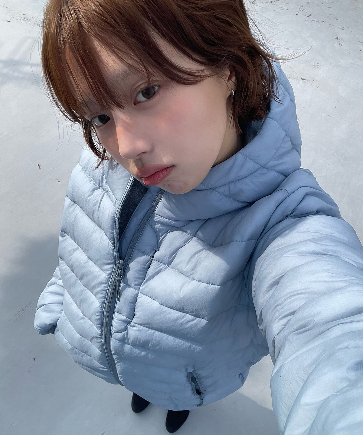 패딩의 얇은 겉감 두께감을 보여주기 위해 손가락으로 원단을 살짝 집어본 모습