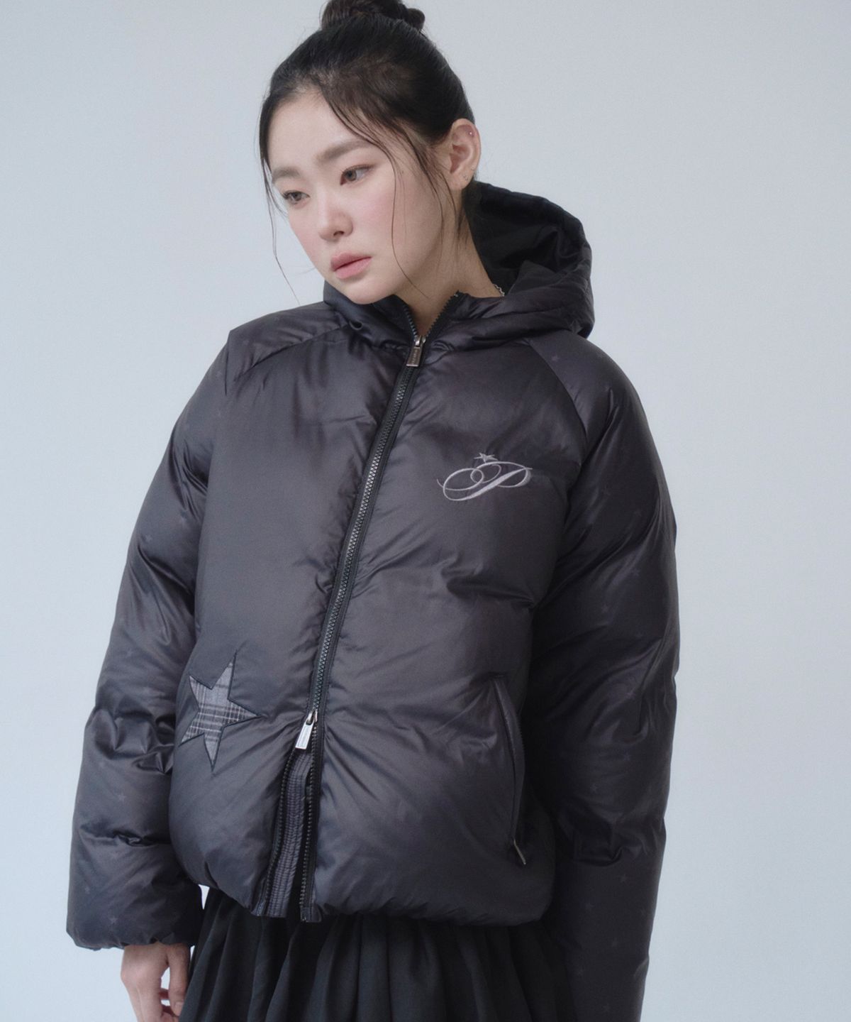 블랙 체크 패턴의 다운 자켓이 옷걸이에 걸려 있는 전체 샷, 가슴 부분의 별 패치가 돋보이는 모습