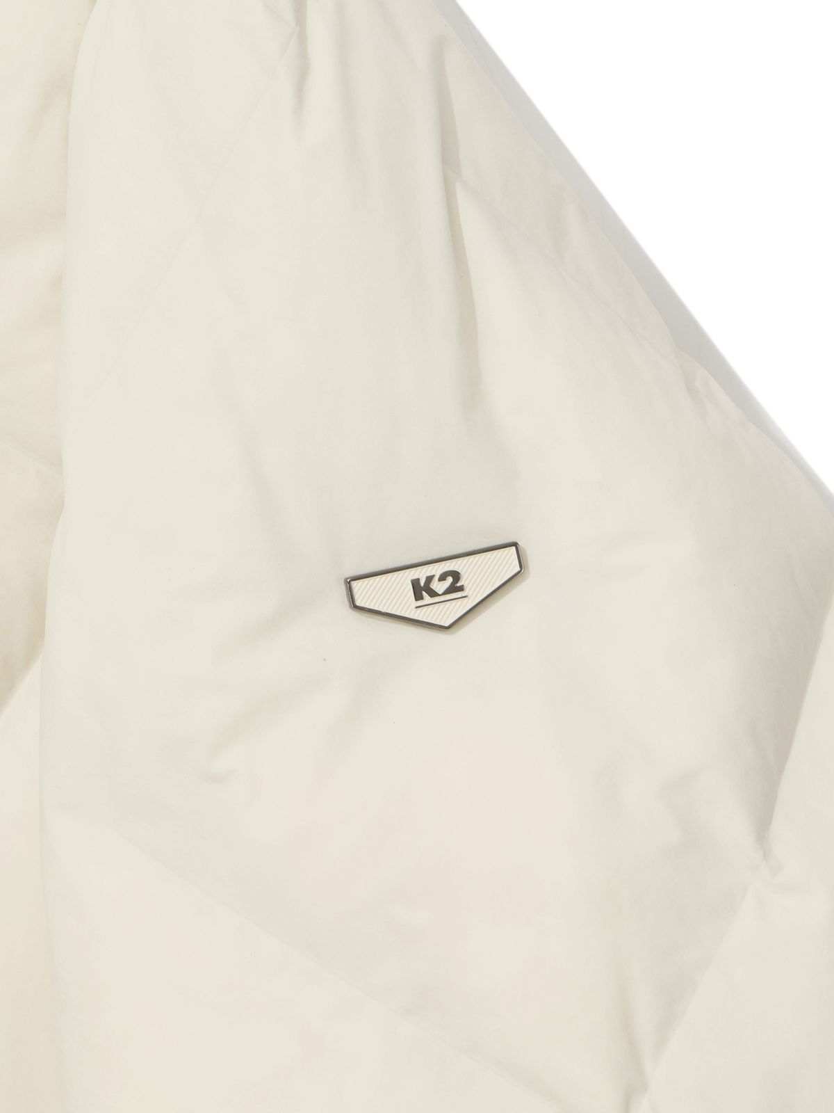 크림색 패딩 소매 부분의 정교한 스퀘어 퀼팅 봉제선과 부드러운 원단 질감을 가까이서 촬영한 디테일 컷
